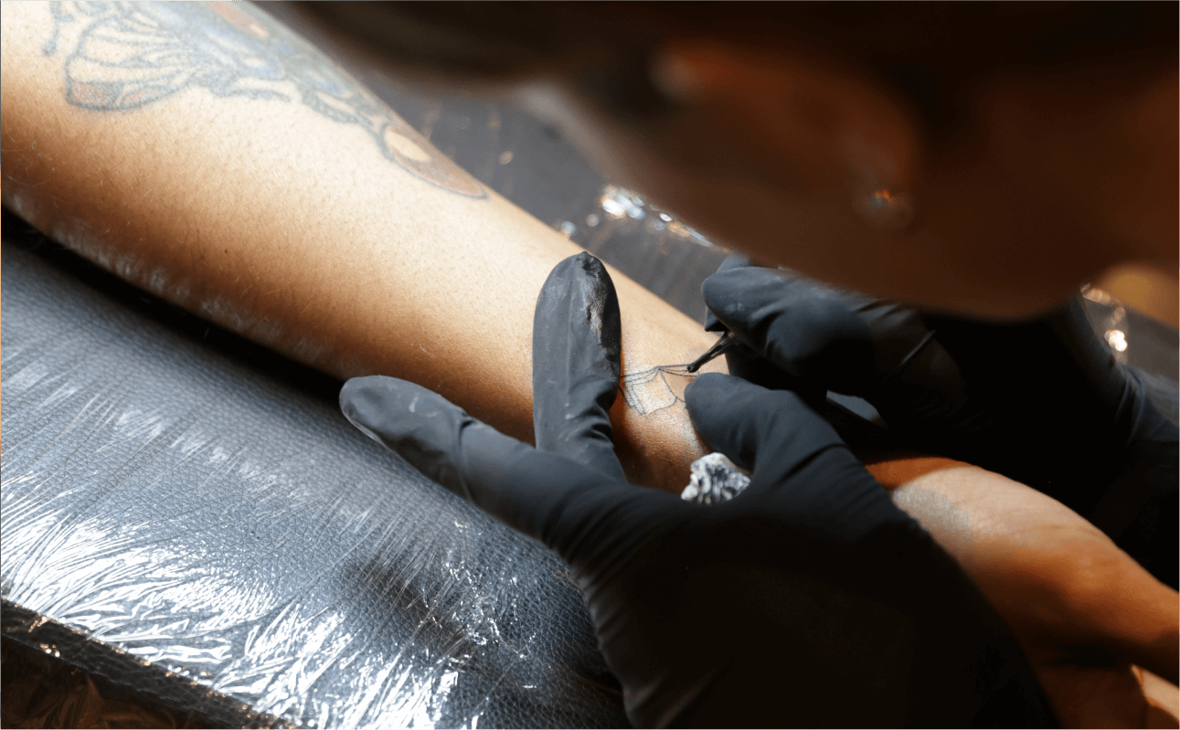 Tattoo artist in action, creating custom tattoos for guests at an exclusive brand activation or special event, offering a unique experience.